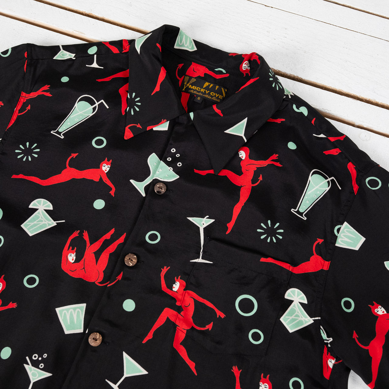 Micky Oye Aloha Shirt mit auffälligem Allover-Print aus roten Teufelsfiguren und Cocktail-Motiven auf schwarzem Hintergrund.