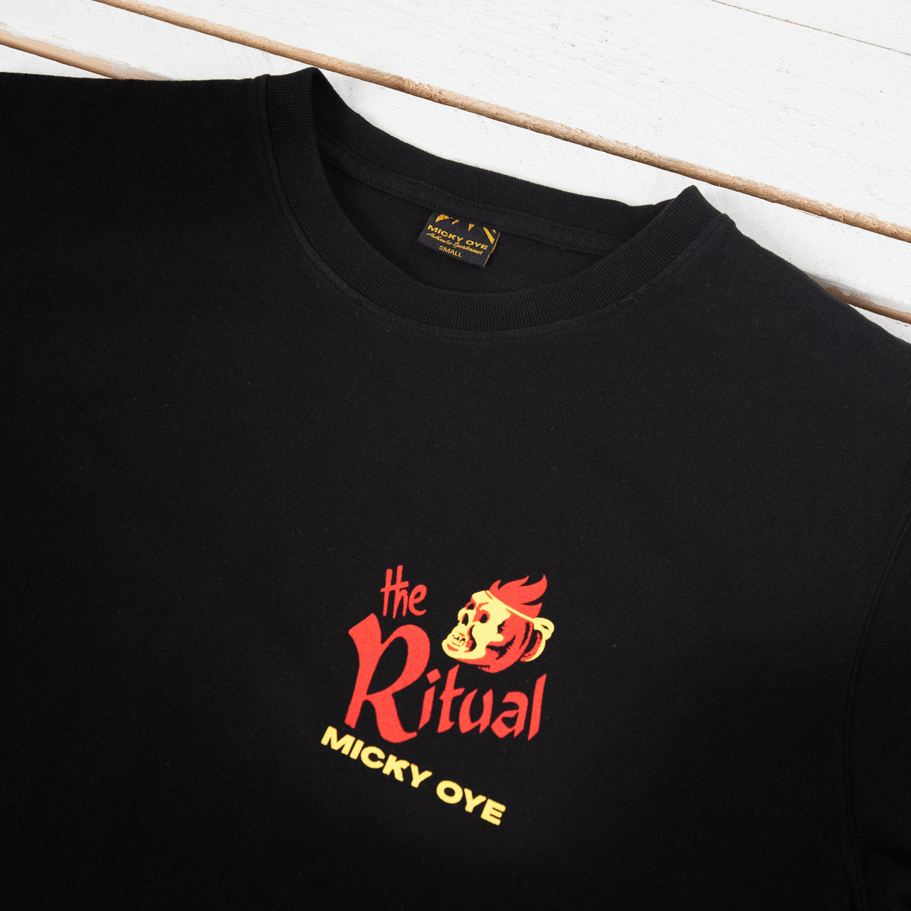 Micky Oye T-Shirt in Schwarz mit Print The Ritual, Detailansicht des Prints und des Kragens, flach liegend