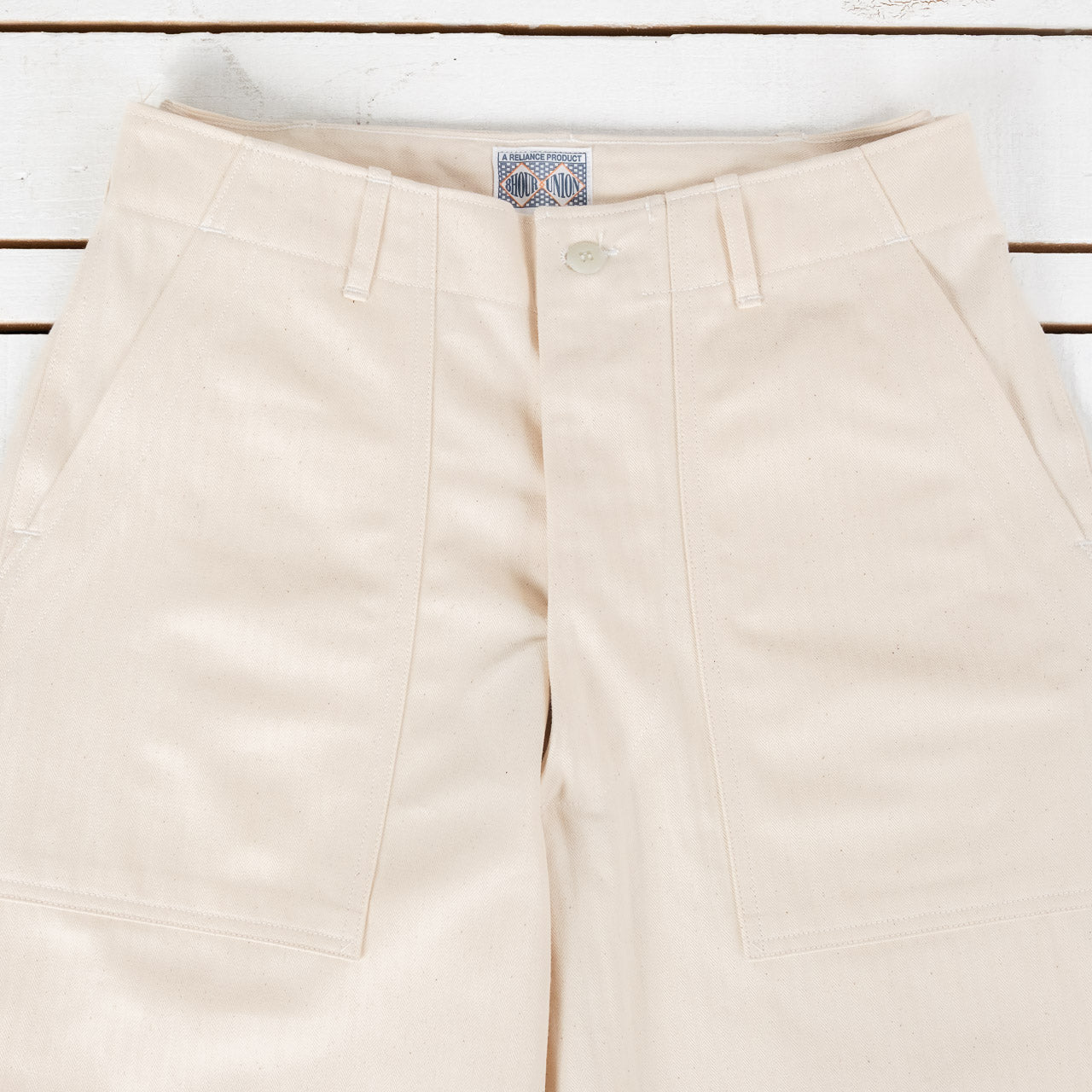 The Real McCoys Fatigue Pants in Ecru, Detailansicht von vorne, flach liegend auf weißem Untergrund