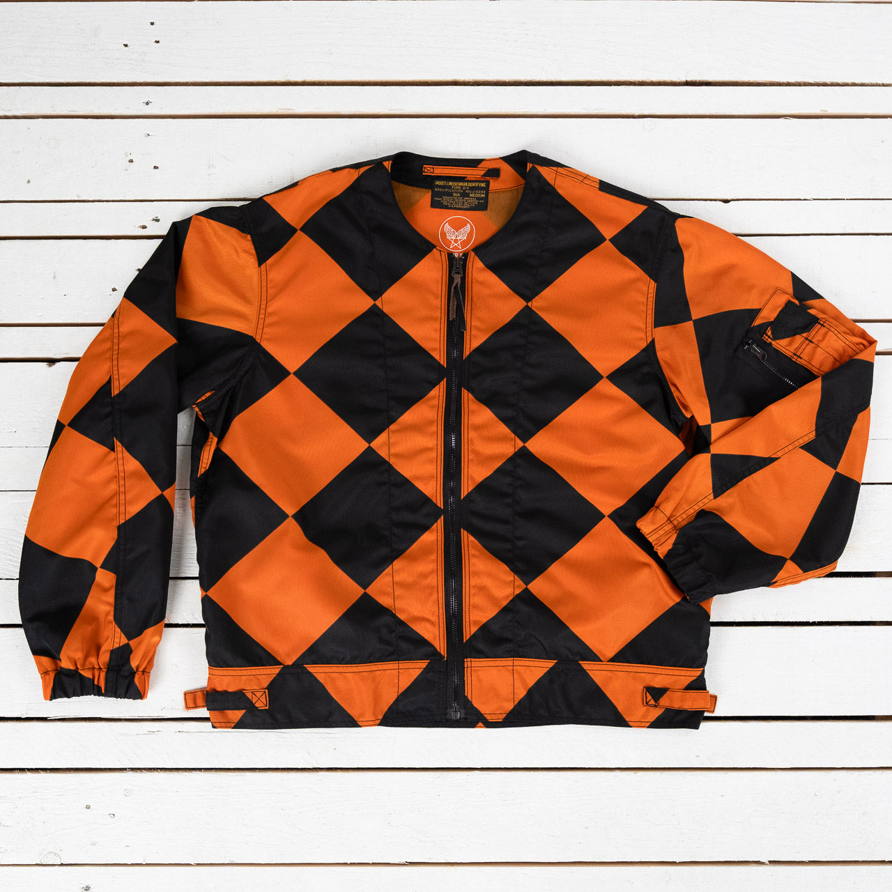 The Real McCoys Linecrewman Jacke mit großem Rautenmuster in Schwarz und Orange, kragenlose Jacke mit Reißverschluss, Ansicht von vorne, flach liegend