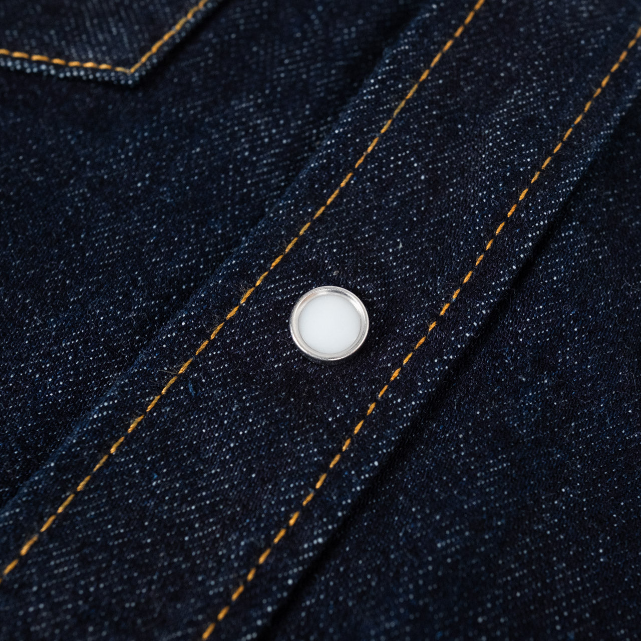 Studio D'Artisan Denim Western Shirt in Indigo, Detailansicht eines weißen Perlmutt-Knopfes an der vorderen Knopfleiste