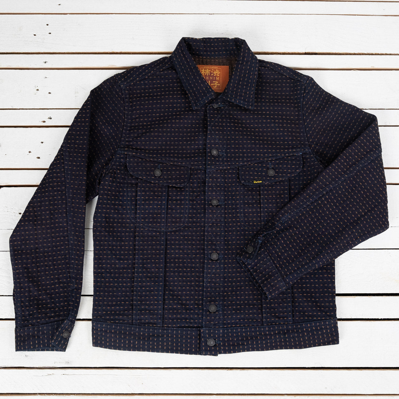 Studio D'Artisan Kakishibu Sashiko Denim Jacke in Indigo, Ansicht von vorne, flach liegend auf weißem Untergrund