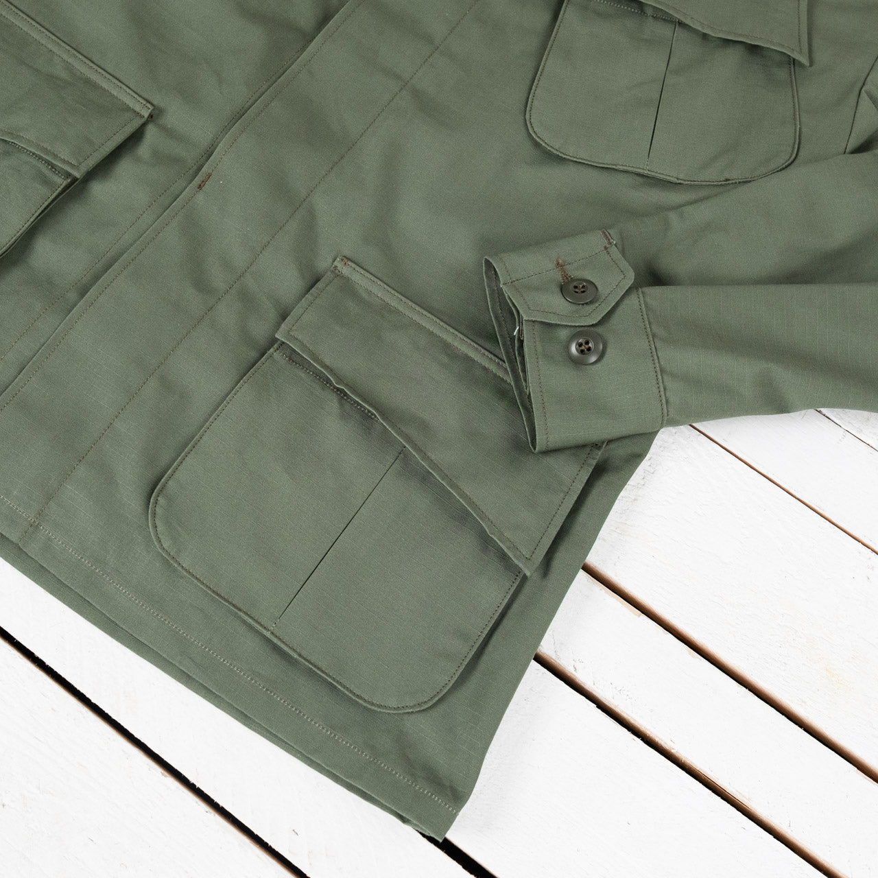 The Real McCoys Ripstop Jacke in Oliv, Detailansicht der vorderen Taschen und des Ärmels, flach liegend
